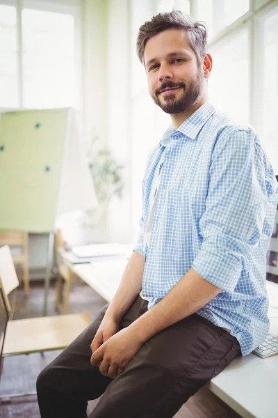 Businessman sitting on desk in office — Stock Photo, Image