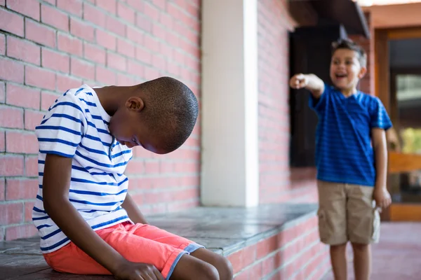 Jongen lachen op trieste klasgenoot in gang — Stockfoto