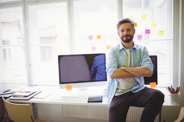 Businessman sitting on desk in creative office — Stock Photo, Image