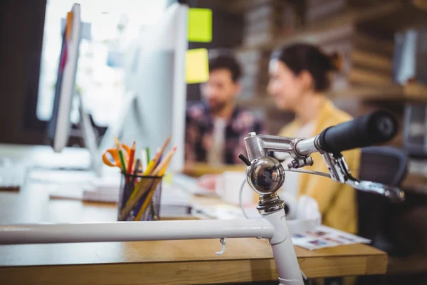 Fahrrad am Schreibtisch, während Geschäftsleute arbeiten — Stockfoto