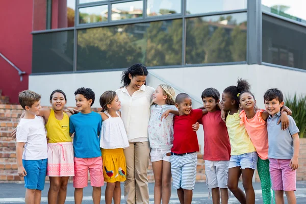 Teacher with children standing outside school — Stock Photo, Image