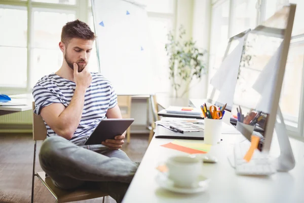 Homme d'affaires réfléchi tenant tablette dans le bureau — Photo