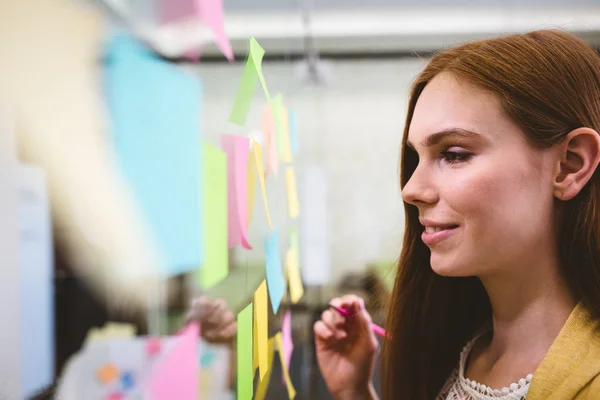 Business woman writing on sticky notes — стоковое фото