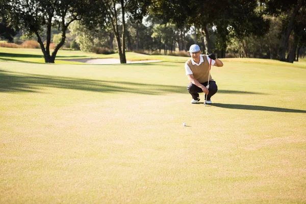 Golfspelare hukande och ser hans boll — Stockfoto