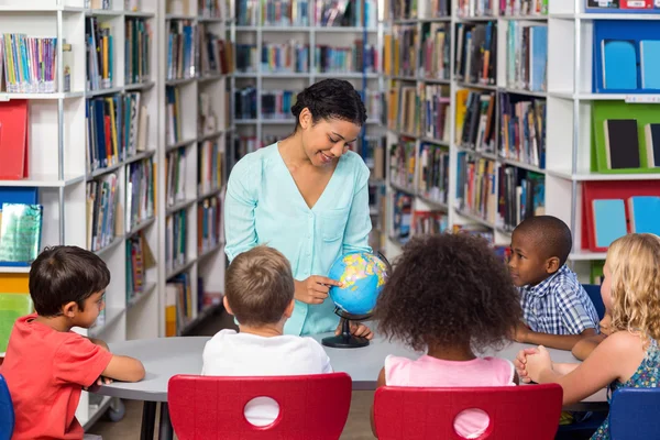 Insegnante insegnare ai bambini utilizzando globo sul tavolo — Foto Stock