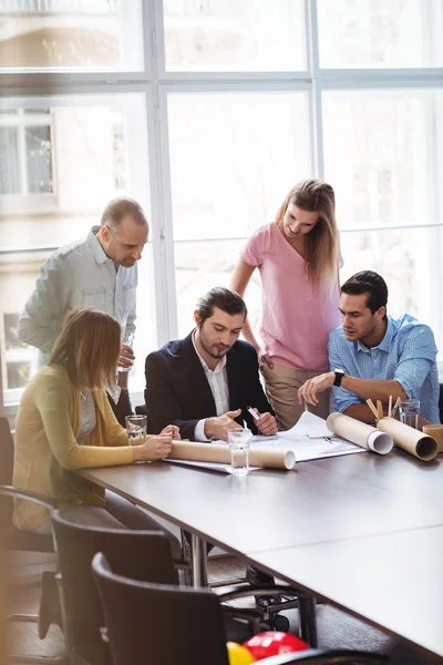 Mensen uit het bedrijfsleven met blauwdruk in een vergaderzaal — Stockfoto