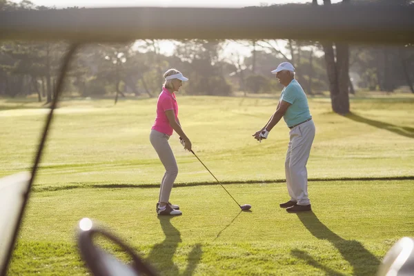 Homem que ensina a mulher a jogar golfe — Fotografia de Stock