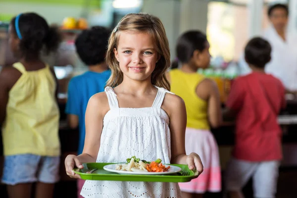 Schoolgirl holding tray in canteen — Stock Photo, Image