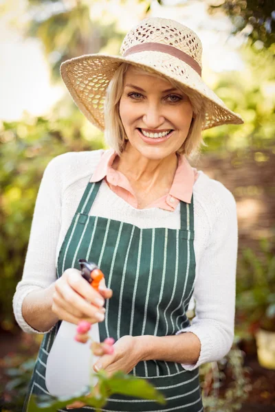 Mulher sorrindo ao regar plantas — Fotografia de Stock