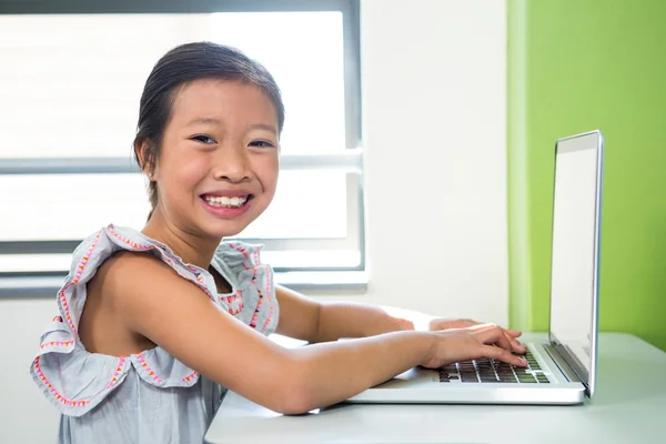 Flickan med laptop på bord i klassrummet — Stockfoto