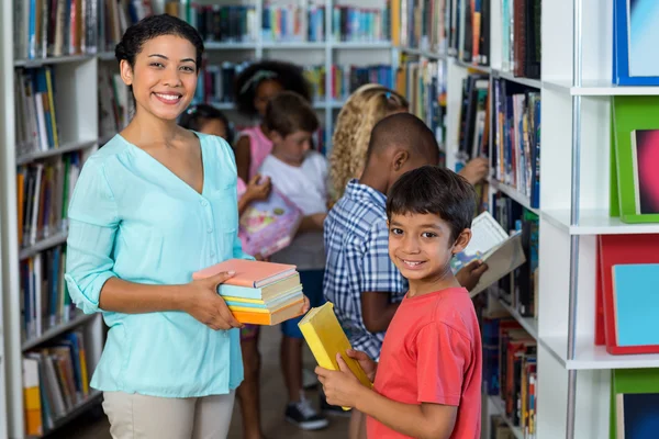 Uśmiechający się Nauczycielka daje książek do chłopca — Zdjęcie stockowe