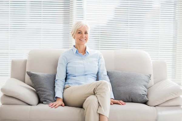 Uśmiechnięta kobieta senior na kanapie — Zdjęcie stockowe