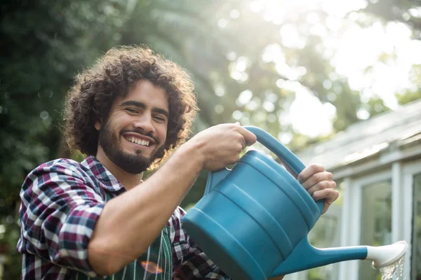 Счастливый садовник поливает снаружи теплицы — стоковое фото