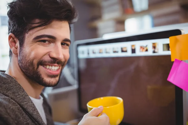 Businessman holding coffee cup by computer — Stock Photo, Image