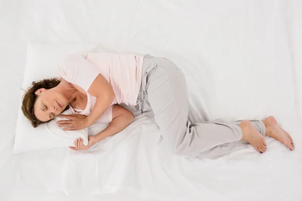 Mujer madura durmiendo en la cama — Foto de Stock