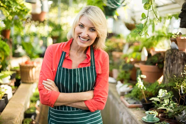 Vrouwelijke tuinman temidden van planten op broeikasgassen — Stockfoto