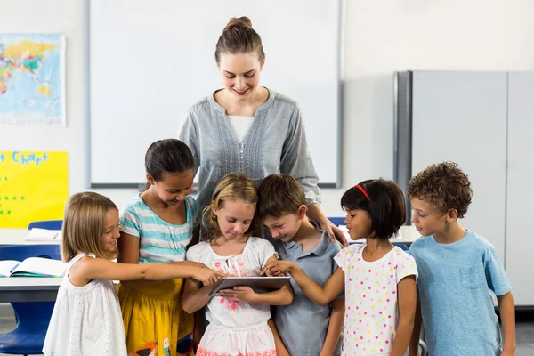 Lärare ser på skolbarn använder digital tablet — Stockfoto