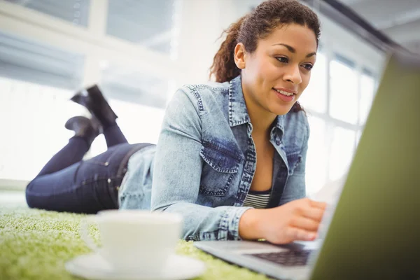 Businesswoman lying on carpet using laptop — Stock Photo, Image