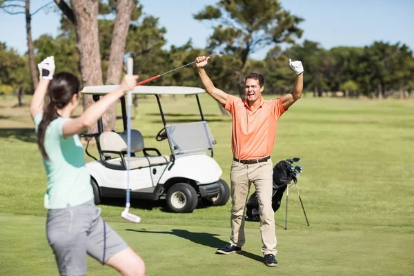golfer couple with arms raised