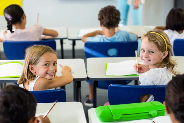 Flickorna sitter med klasskamrater i klassrummet — Stockfoto