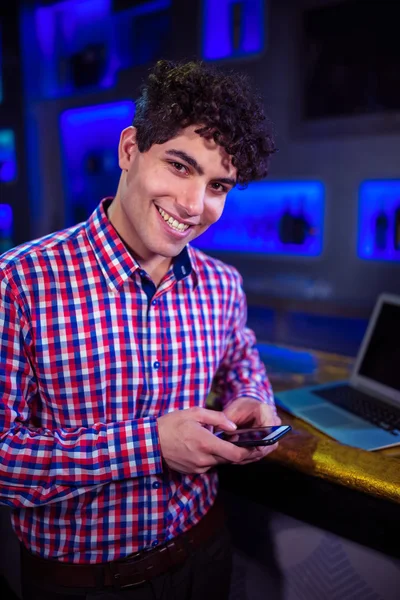 Man holding mobile phone by bar counter — Stock Photo, Image