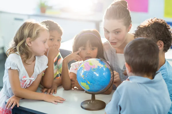 Lehrerin zeigt Schülern Globus — Stockfoto