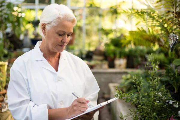 Female scientist writing in clipboard — Stock Photo, Image