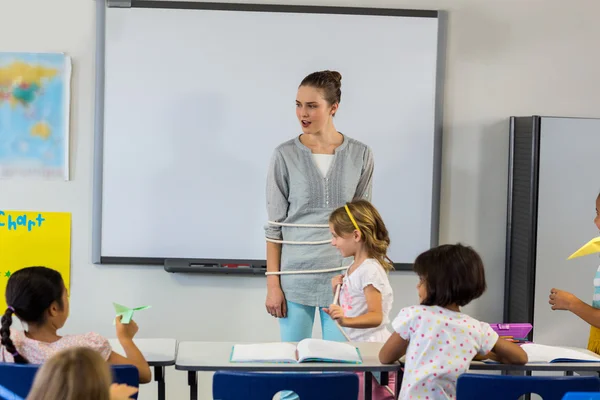 Anak-anak mengikat guru perempuan di kelas — Stok Foto