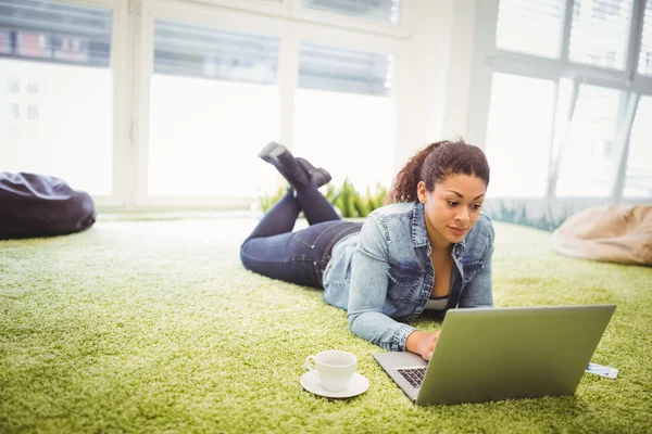 Empresária usando laptop deitado no escritório criativo — Fotografia de Stock