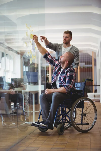 Handicap hombre de negocios con colega pegando notas —  Fotos de Stock