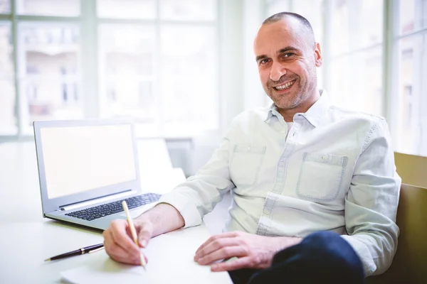 Un homme d'affaires souriant écrit un document — Photo