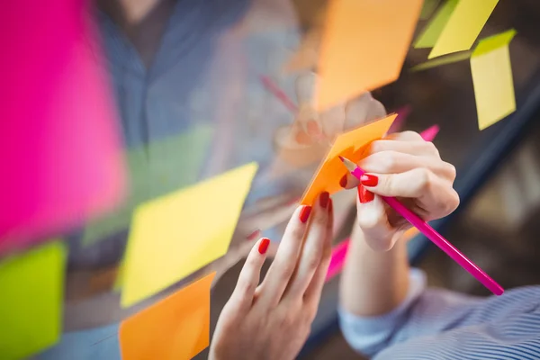 Businesswoman writing on sticky notes — Stock Photo, Image