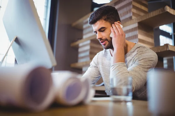 Businessman using cellphone at computer desk — Stock Photo, Image