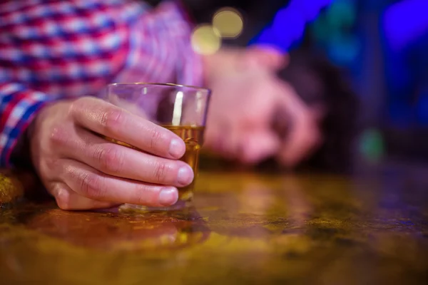 Man with whiskey glass lying on bar counter — Stock Photo, Image