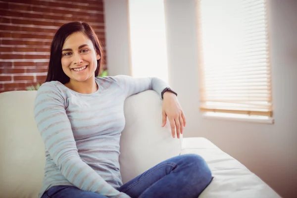 Wanita tersenyum duduk di sofa — Stok Foto