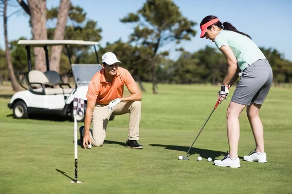 Mulher jogando golfe enquanto está de pé pelo homem — Fotografia de Stock