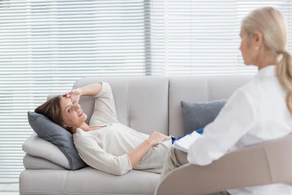 Женщина, лежащая на диване и разговаривающая с терапевтом — стоковое фото