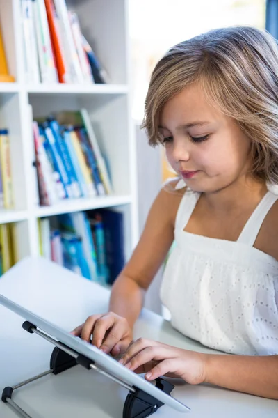 Menina elementar usando tablet na biblioteca — Fotografia de Stock