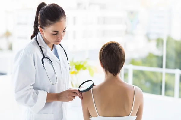 Médico examinando paciente com lupa — Fotografia de Stock