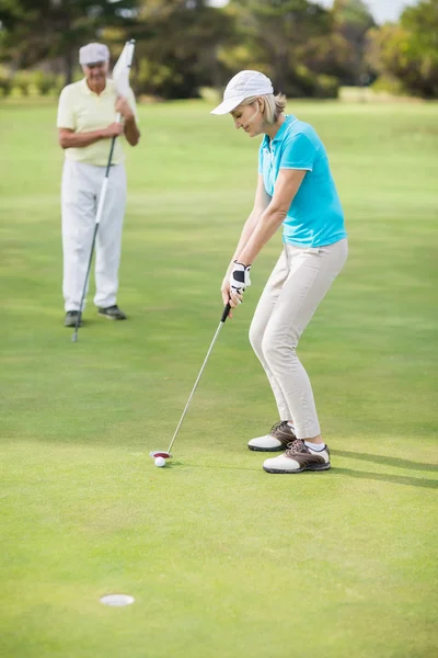 Женщина играет в гольф, стоя рядом с мужчиной — стоковое фото