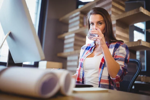 Бізнес-леді п'є воду в креативному офісі — стокове фото