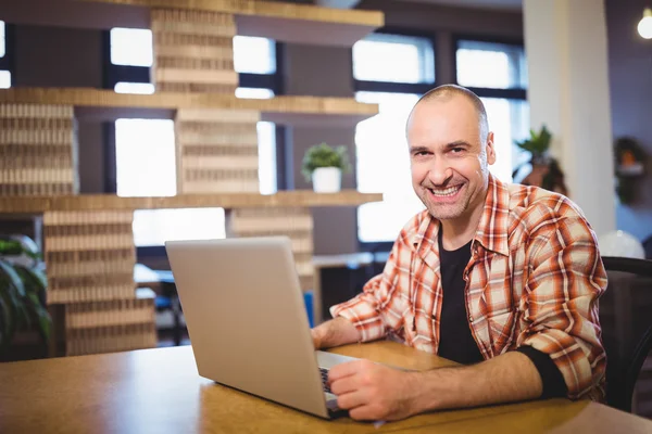 Businessman using laptop at desk in creative office — Stock Photo, Image