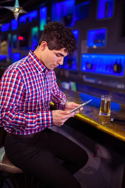 Человек с помощью цифрового планшета на барной стойке — стоковое фото