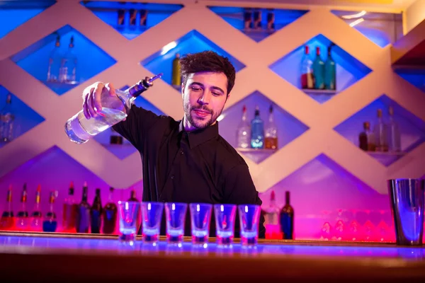 Barman nalévání alkoholu v panácích — Stock fotografie