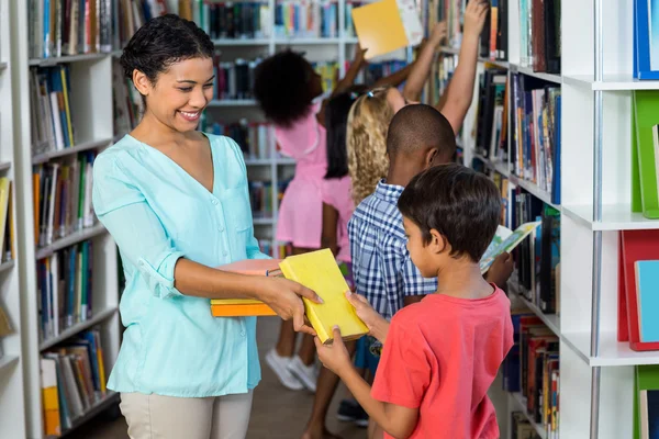 Teacher giving books to boy — Stock Photo, Image