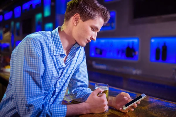 Homem usando telefone celular no balcão de bar — Fotografia de Stock