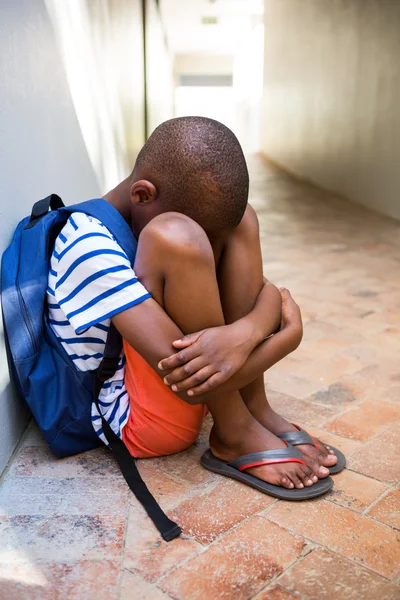 Chico triste sentado en el pasillo en la escuela — Foto de Stock