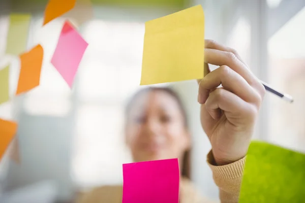 Businesswoman writing on adhesive note — Stock Photo, Image