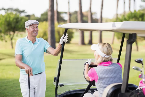 Man looking at woman sitting in golf buggy — Stock Photo, Image