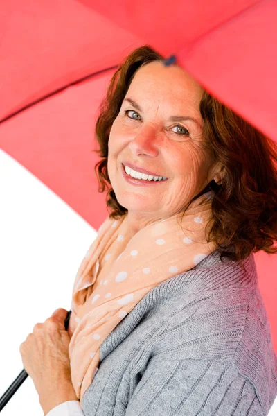 Mulher madura segurando guarda-chuva vermelho — Fotografia de Stock